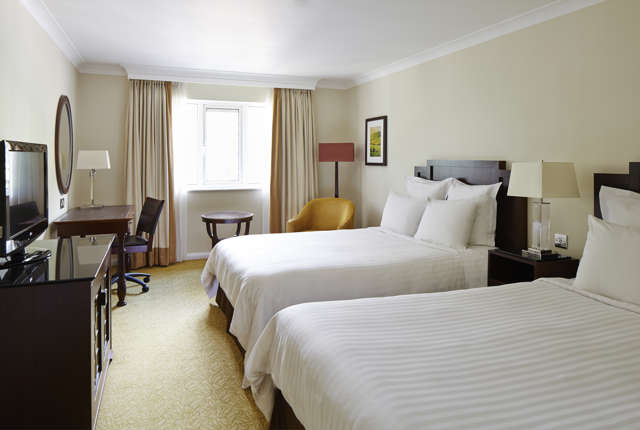 Twin guest room at Forest of Arden near Birmingham with two beds, desk, armchair and bright window with curtains