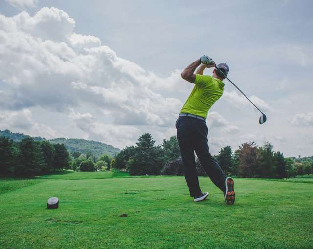 Forest of Arden golf course near Birmingham with golfer teeing off on a fairway beneath dramatic clouds